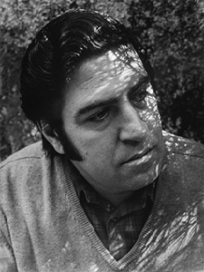 Man with shadows on face, looking thoughtfully.