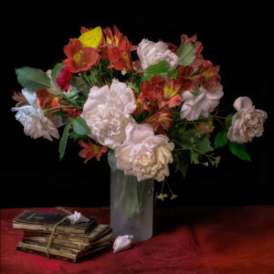 A vase of flowers and two books on a table.