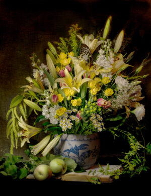 A vase filled with flowers next to some apples.