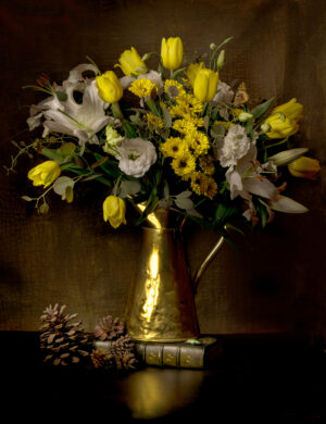 A vase of flowers on the table with pinecones.