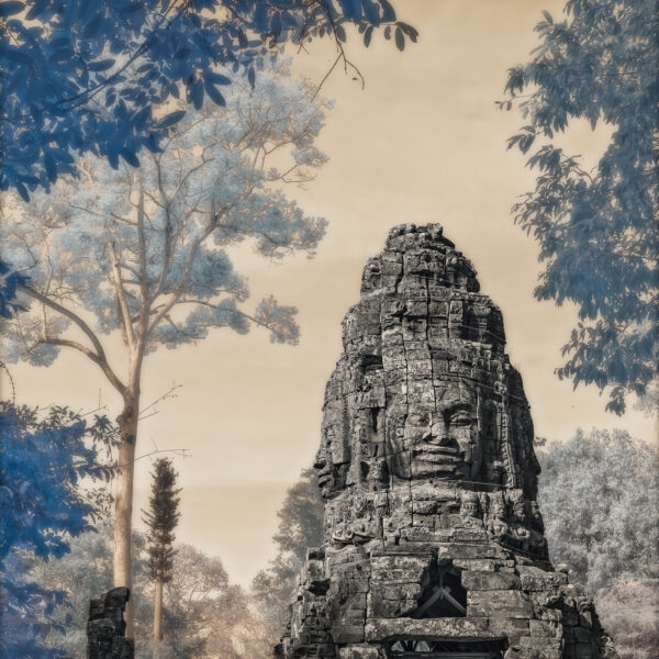 A stone statue of faces in the middle of trees.