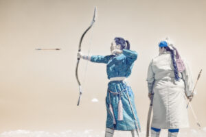 Two people in blue and white costumes are holding a bow and arrow.