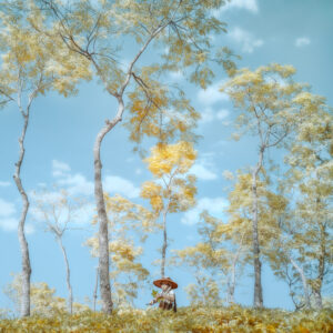 A painting of trees and bushes with one person standing in the background.