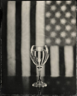 A glass of water is in front of the american flag.