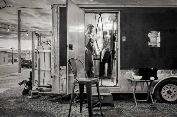 A black and white photo of two men in a trailer.