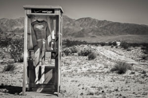 A black and white photo of an outhouse with a dress on it.