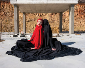 A woman in red and black sitting on the ground