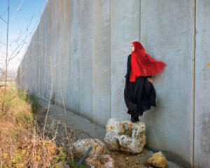 A woman in red is leaning against the wall