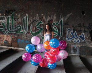 A woman standing in front of balloons on the ground.