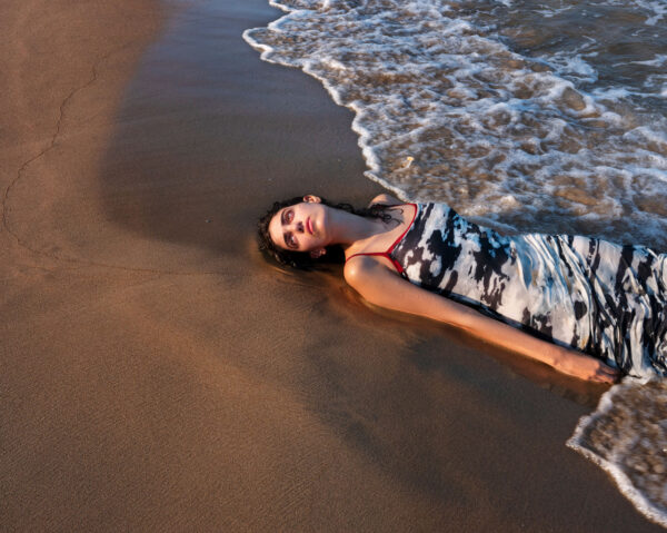 A woman laying in the sand on top of a beach.