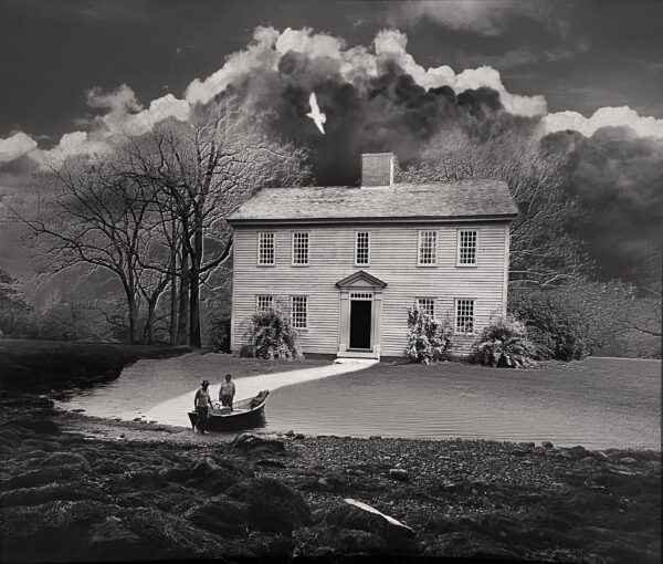 A black and white photo of a house with clouds in the background.