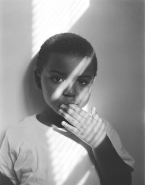 A young boy with his hand over his mouth.