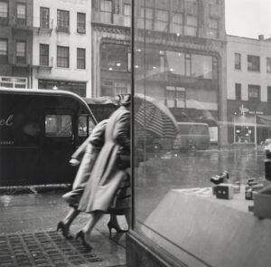 A black and white photo of two people walking down the street