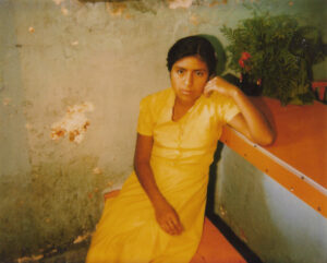A woman in yellow dress sitting on steps.