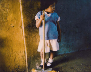 A young girl is standing in front of the wall and mops.