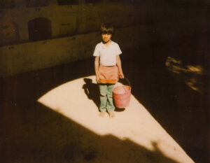A young girl holding a bucket in the sunlight.