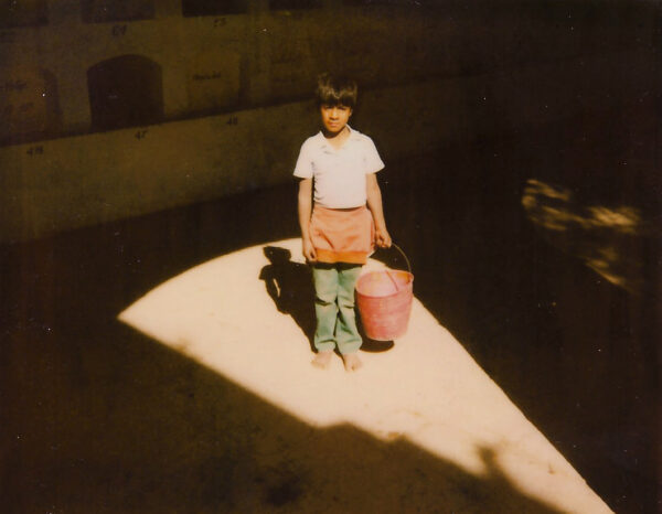 A young girl holding a bucket in the sunlight.