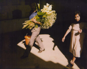 A man holding flowers while walking next to a woman.