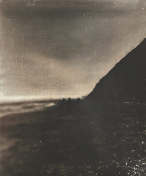 A black and white photo of the ocean shore.