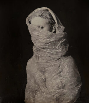 A dog wrapped in plastic and looking like it is wrapped.