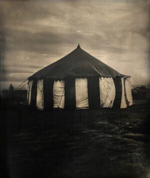 A tent with white curtains on top of it.