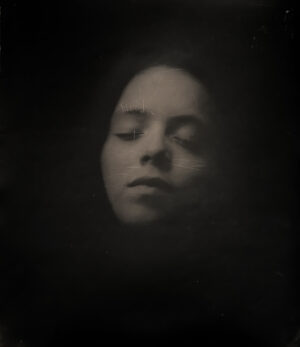 A woman is in the dark with her eyes closed.