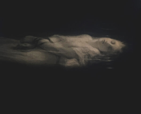 A woman is lying in the dark with clouds.