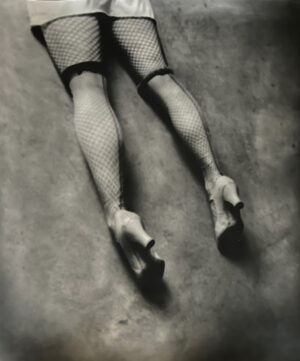 A woman 's legs in fishnet stockings and high heels.