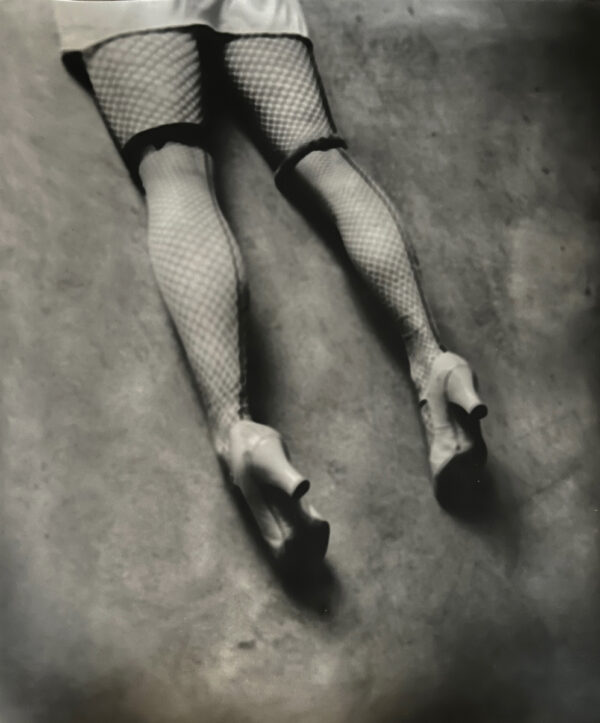 A woman 's legs in fishnet stockings and high heels.