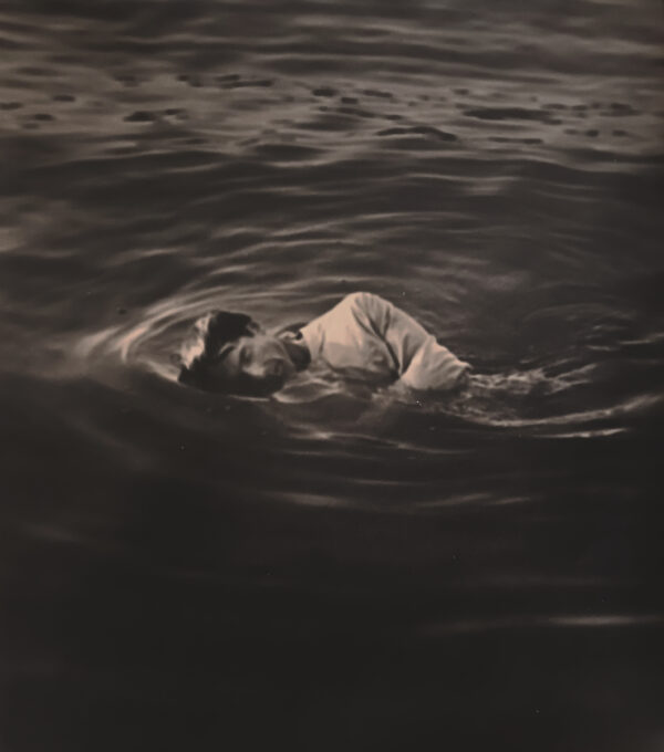A person swimming in the water with their head above the surface.