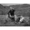 A woman sitting on the ground with her dog.
