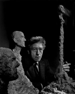 A man in suit and tie next to some sculptures.