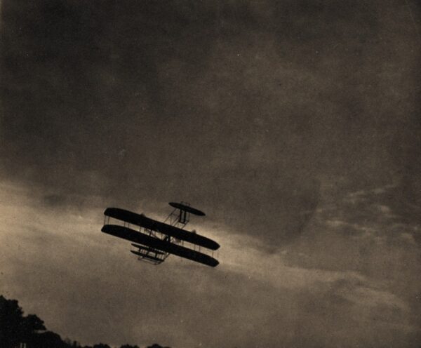 A plane flying in the sky with clouds above it.