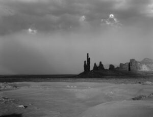 A black and white photo of the ocean with a castle in the background.