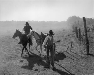 A man on horseback and another man in cowboy gear.