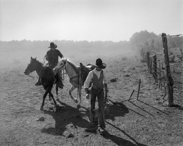 A man on horseback and another man in cowboy gear.