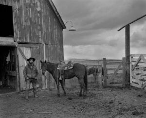 A man and his horse in front of an old barn.