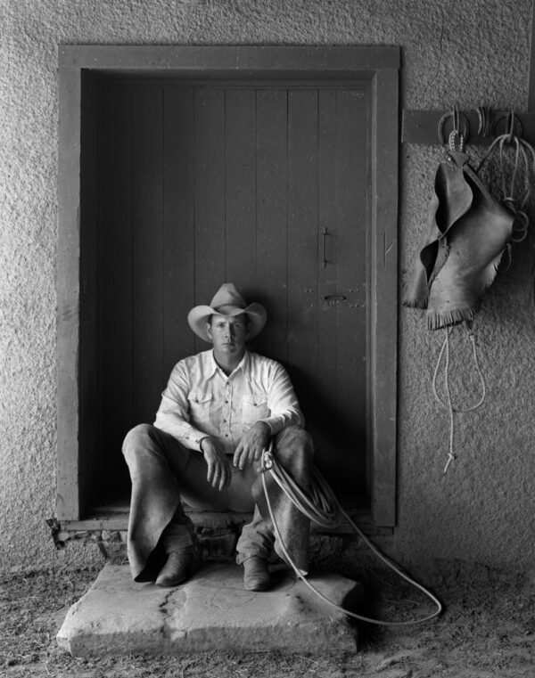 A man sitting on the ground in front of a wall.