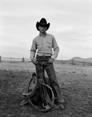 A man in cowboy hat standing on top of a bicycle.