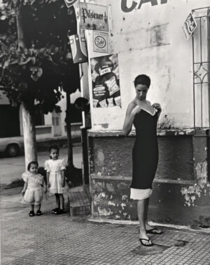A woman and two children stand on the sidewalk.