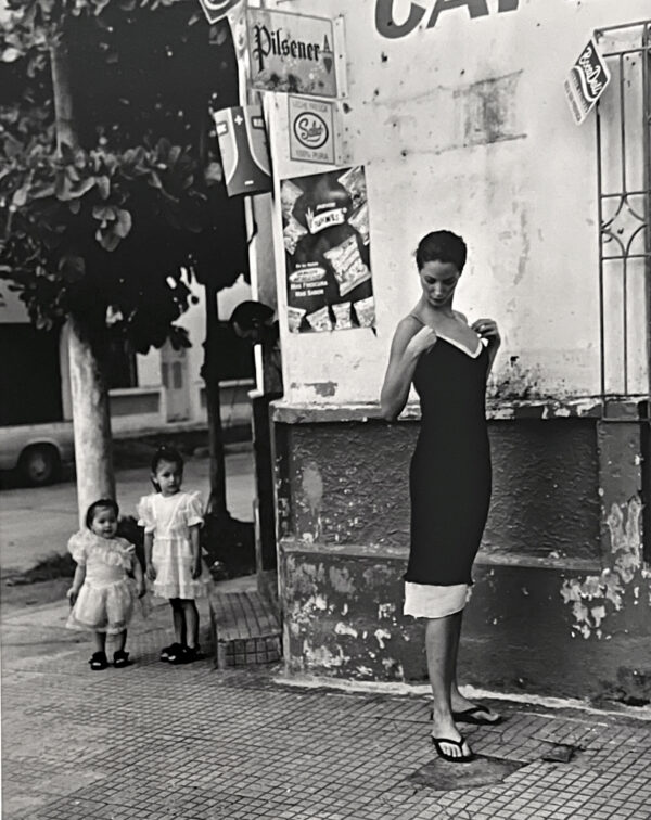 A woman and two children stand on the sidewalk.