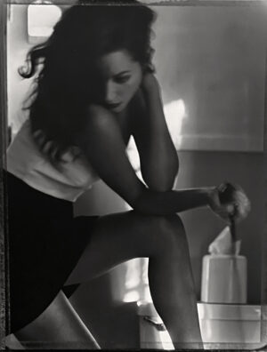 A woman in white shirt and black skirt holding onto a pole.