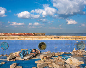 A person laying on the ground near some rocks