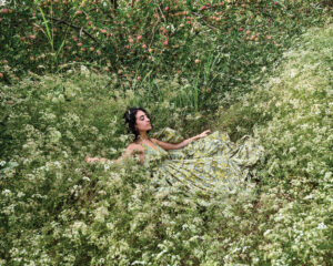 A woman in a dress is sitting in the grass