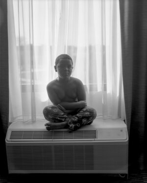 A statue of a person sitting in front of a window.