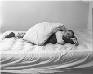 A person laying on top of a bed with pillows.