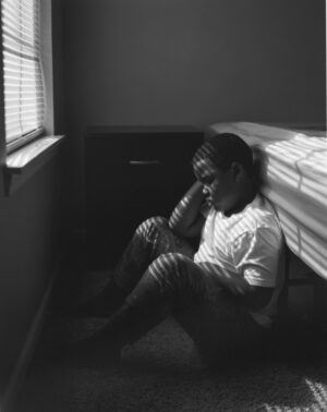 A person sitting on the floor in front of a window.