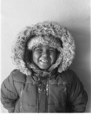 A young child wearing a jacket and fur hat.