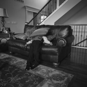 A person sitting on top of a couch in front of a staircase.