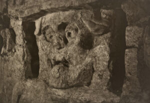 A stone carving of a face in the middle of a wall.